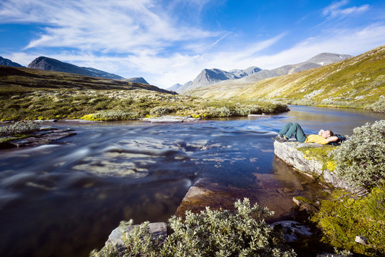 Rondane National Park, Norway: A male hiker by the river that flows from the Rondvassbu lodge towards Otta and comes by the parking in Spranget.