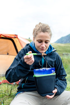 Llyn Idwal (lake), Snowdonia National Park, Bangor, Wales, United Kingdom: A woman enjoying her instant dinner in the mountains.