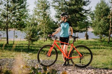 Young pretty woman holding bicycle outdoors at the park