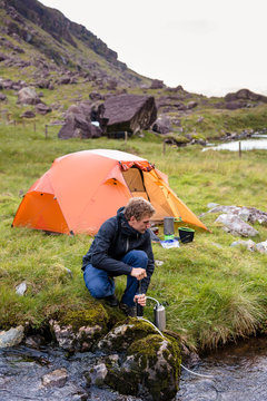 Mount Brandon, Faha, Kerry, Ireland: Camping about half way up Mount Brandon (952m), the ninth highest mountain of the island. A man is filtering water in front of the tent.