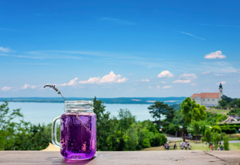 Tihany abbey with the lake Balaton blurred in the background and a lavender beverage focused in the...