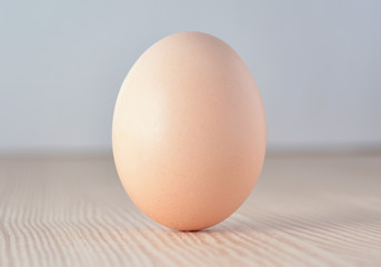 Egg standing on its fat end on wooden surface.