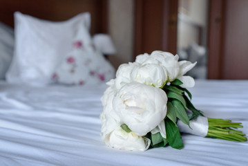 Bouquet of flowers of the bride on bed in bedroom. Wedding preparing.