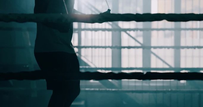 Cinematic slow motion shot of a professional young muscular african man is jumping rope before shadow boxing work out in a ring. 