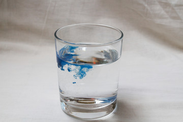 A drop of blue paint in a glass of water