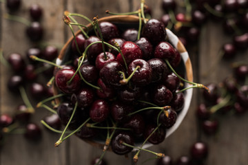 top view of red, fresh, whole and ripe cherries covered with droplets on bowl