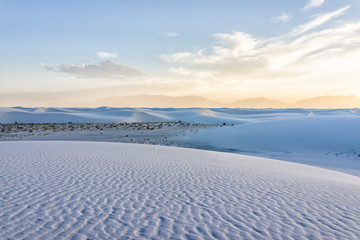 White sands dunes national monument in New Mexico with horizon at sunset with silhouette of Organ Mountains