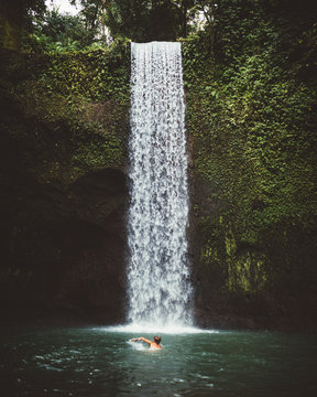 Man swimming under waterfall
