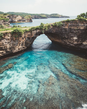 Landscape of peaceful tropical blue bay behind natural archway of cliff in tropical landscape, Bali