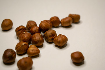 Several varieties of nuts are located on a white sheet of paper.