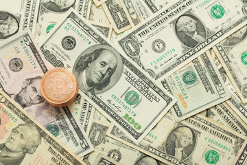 Stack of Bitcoin coins on dollar currency bills.