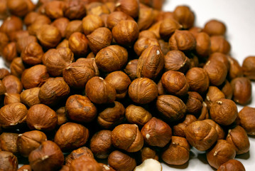 Several varieties of nuts are located on a white sheet of paper.