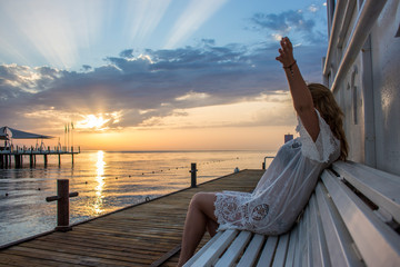 Fototapeta premium A girl with a special philosophy meets the sun every morning raising her hands up.