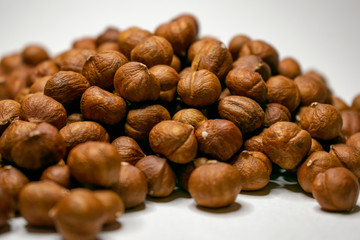 Several varieties of nuts are located on a white sheet of paper.