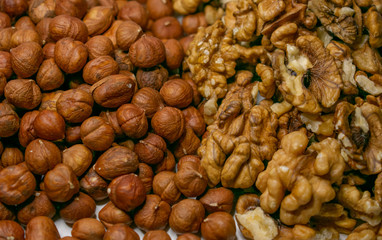 Several varieties of nuts are located on a white sheet of paper.