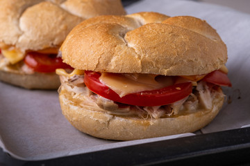 Two homemade burger Vienna Kaiser bread bun bread roll with chicken meat tomato mustard mayonnaise on baking tray sheet parchment paper white background