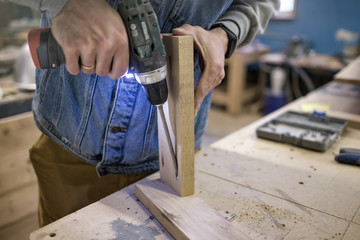 Woodwork and furniture making concept. Caucasain man carpenter installs the furniture hinge. Pocket...