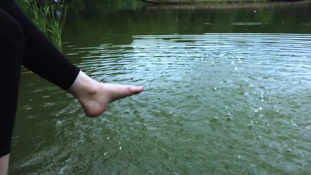 The girl sits on the platform and splashes water feet