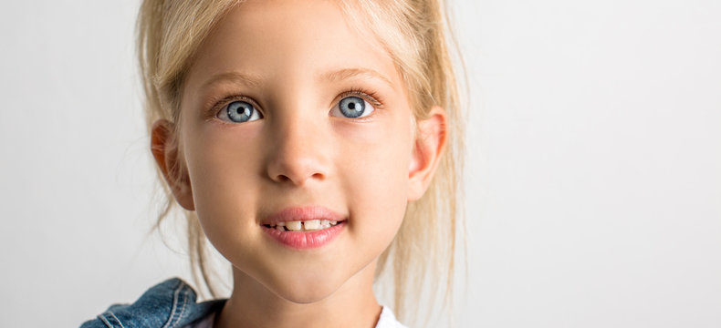 Beautiful blond girl of seven years old, big blue eyes, close-up, white background