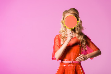 girl covering face with hand mirror and posing isolated on pink, doll concept