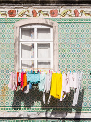Colorful laundry drying in front of a window of a traditional tiled building in Torres Vedras, Portugal