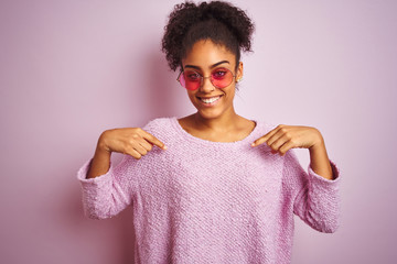 African american woman wearing winter sweater and sunglasses over isolated pink background looking...