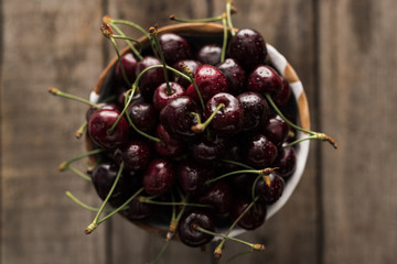 top view of red, fresh, whole and ripe cherries covered with droplets on bowl