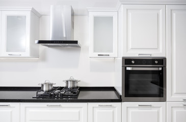 White glossy kitchen furniture with equipment and pots on a cooker