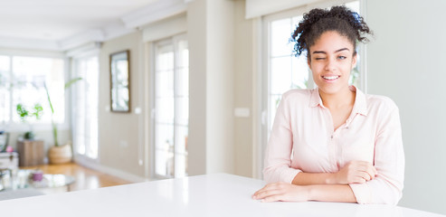 Wide angle of beautiful african american woman with afro hair winking looking at the camera with...
