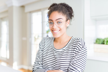 Beautiful young african american woman with afro hair wearing glasses with a happy and cool smile...
