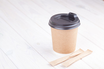 Craft paper coffee cups on a white table near light wall background