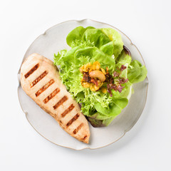 Grilled chicken fillet with salad served on a plate, isolated on white background