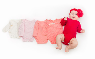 A four month happy baby in red bodysuit lying on a white background with pink clothes smaller size.