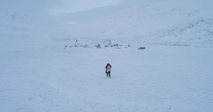 Aerial view of Siberian life in the my of yurts camp , man walking through the snow wearing clothes from fur.