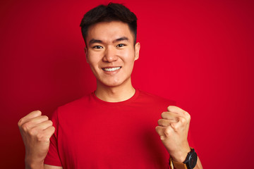 Young asian chinese man wearing  t-shirt standing over isolated red background screaming proud and celebrating victory and success very excited, cheering emotion