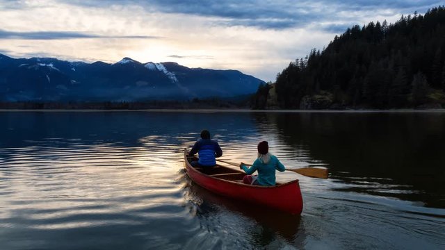 Cinemagraph of Adventurous people on canoe enjoying the beautiful Canadian Mountain Landscape during a vibrant sunset. Taken in Harrison River, East of Vancouver, British Columbia, Canada. Animation