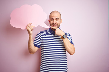 Young man holding speech bubble with blank space for message over pink isolated background very happy pointing with hand and finger