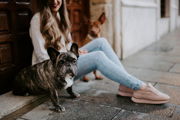 Trendy modern woman with bulldog and hound on street side walk smiling