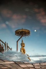 Estatua de buda dorada reflejada en el agua al anochecer en un templo en chiang mai, tailandia