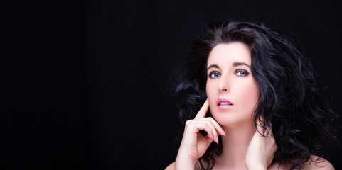 Young attractive woman with long black hair on dark background