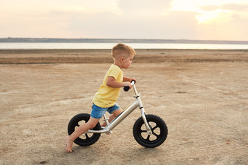 little boy riding bike at sunset beach