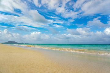 Tropical beach with turquoise waters on a sunny day with dynamic scattered white clouds above