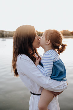 Mother and daughter kissing by lake