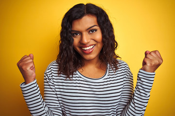 Transsexual transgender woman wearing striped t-shirt over isolated yellow background screaming proud and celebrating victory and success very excited, cheering emotion