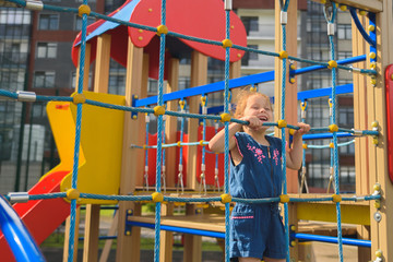 Teenage girl try to climbing on the rope wall. She is playing with the rope wall to develop motor activity at the playground