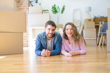 Young beautiful couple in love relaxing lying on the floor together with cardboard boxes around for moving to a new house