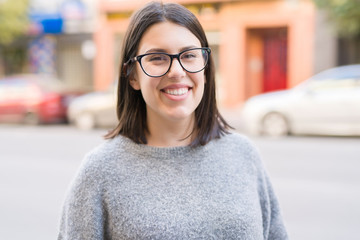 Young beautiful woman wearing glasses smiling confident walking on the street at the city town