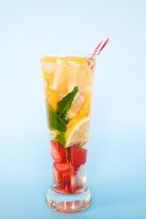 Sweet summer refreshing drink with strawberry, mint, apricot and lemon. Fruit cocktail on blue background.