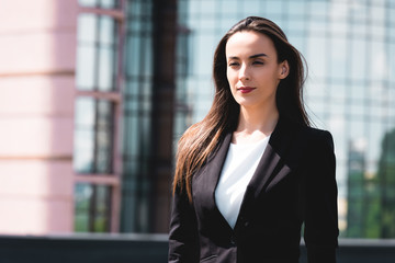 positive, confident businesswoman standing on rooftop and looking away