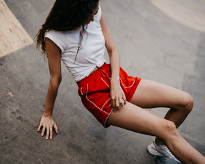 Beautiful skater woman wearing red shorts riding on her longboard in the sunset city